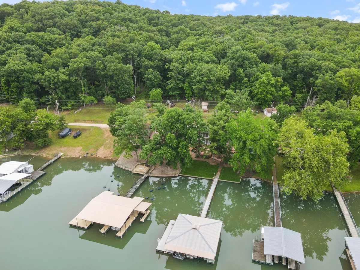 The photo shows a broad view of the dock stretching into the lake, with boats moored and leafy trees framing the shoreline in the background. The scene is calm and inviting, perfect for boating, fishing, or simply soaking in the serene lakeside atmosphere as the sun begins to set.